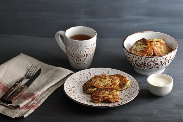 Fritters of zucchini with tea on rustic 