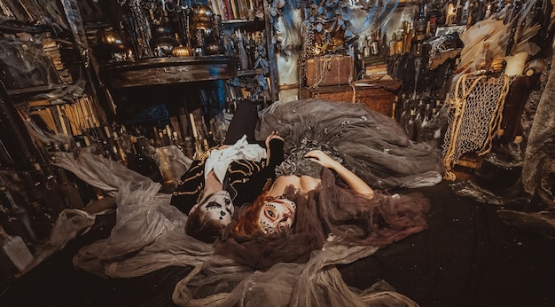 上から神秘的なインテリアのスタジオの床に横たわっているハロウィーンのカップル。ホリデーメイクの男女
