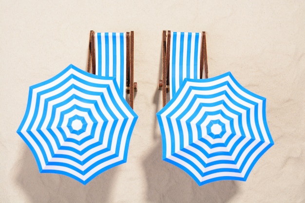 From above shot van gestreepte stoelen onder parasols op het strand.