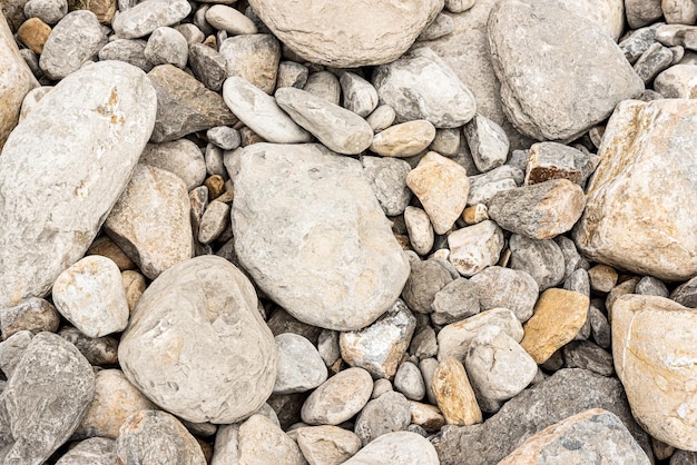 Сверху на фоне различных форм сухие разбросанные серые камни на берегу при солнечном свете