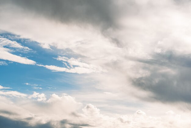 From below of bright sunlight shining through fluffy clouds floating over blue sky