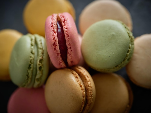 From above closeup pile of delicious sweet round colorful macaroons with different flavors stacked together on table in light room