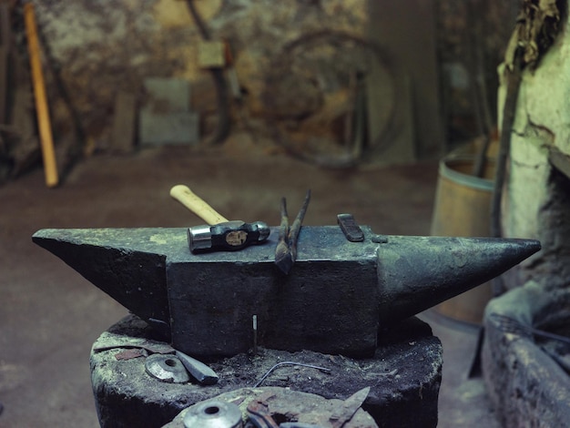 Сверху молоток и щипцы помещены на массивную стальную наковальню в старой ветхой традиционной кузнечной мастерской