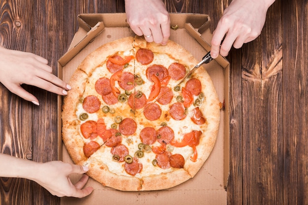 From above hand cutting pizza