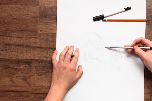 上から鉛筆で絵を描く人の手