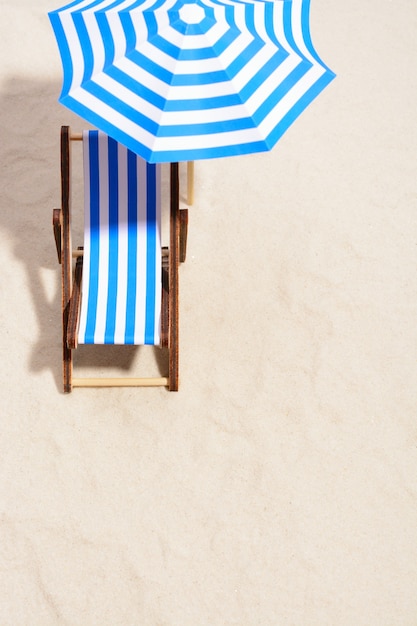 From above of lounge area on beach with striped chair under umbrella.