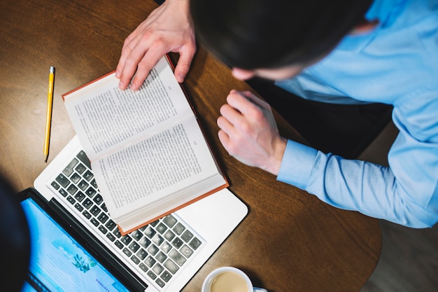 Photo from above man studying with book and laptop