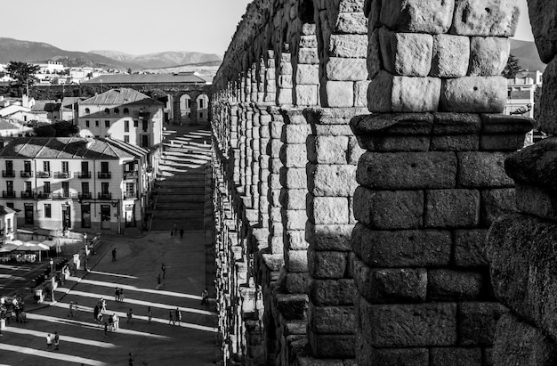 From a perspective with a vanishing point of the arches of the\
segovia aqueduct and people on the stairs