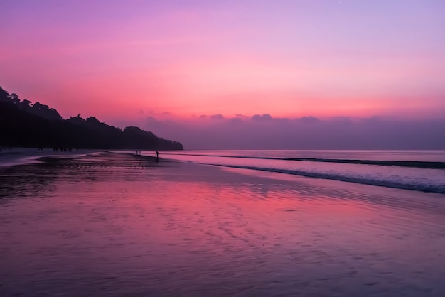 С моря силуэт таллинна с огненным морским закатом. красивый закат на море в красно-оранжевых фиолетовых тонах.