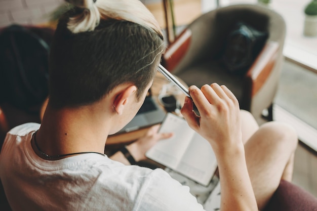 From above shot of anonymous man in casual outfit rubbing forehead with pen and thinking while making notes