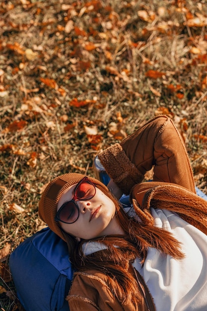 Сверху путешествующая женщина расслабляется и лежит на рюкзаке осенью на природе