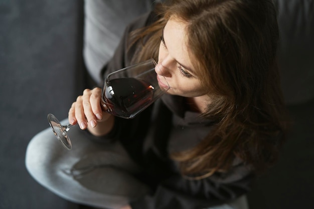 from above woman drinking glass of red wine at home