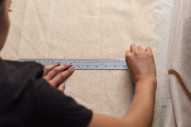 From above woman measuring fabric using rules