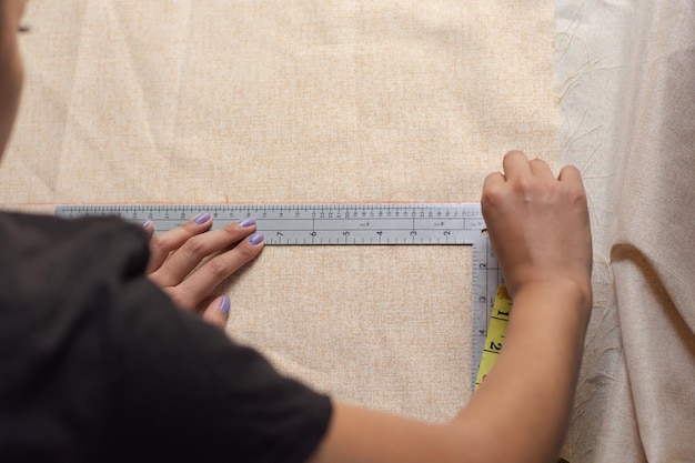 From above woman measuring fabric using rules