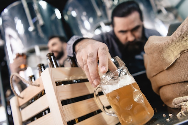 Foto fronsende mens die bier in mokmicrobrewery inspecteren.