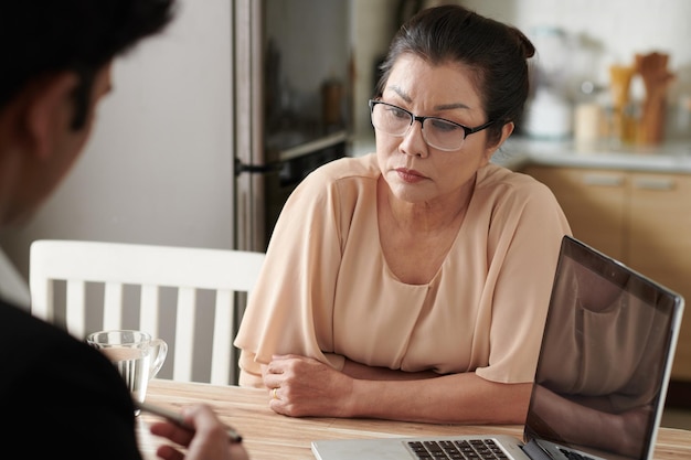 Fronsende serieuze senior vrouw die luistert naar verzekeringsagent die de voordelen uitlegt van het hebben van een verzekering...