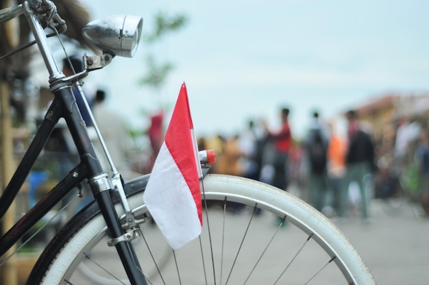 The front of the antique bicycle has an Indonesian flag with a blurred background