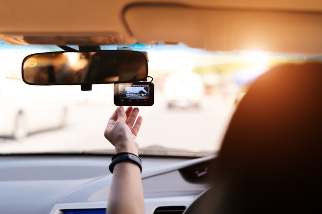 Front camera car recorder, woman set video recorder next to a rear view mirror