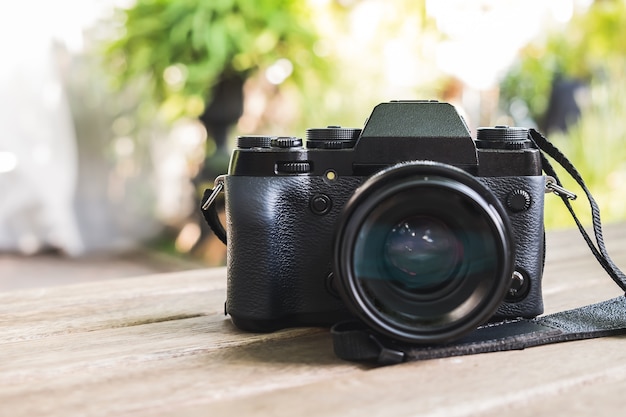 Photo front of digital camera on wood table or wood rack with natural blur background