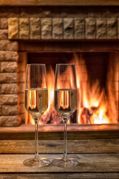 冬の夕方の暖炉の前でシャンパンワインのグラス
