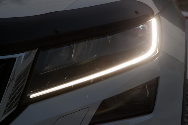 Photo front headlamp view of white car with turn on led day running drl light and bixenon lens