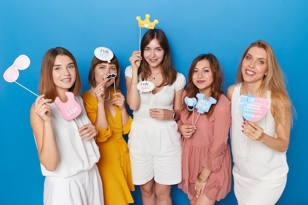 Front image of a group of smiling female models to have gender reveals envent isolated blue background