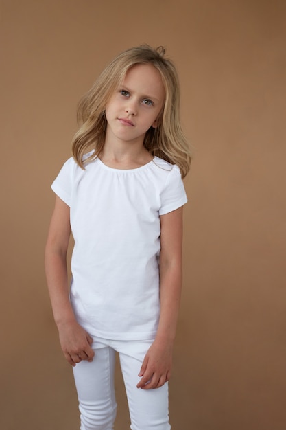 Front image of a little girl with blond hair dressed all in white, with a frowning face