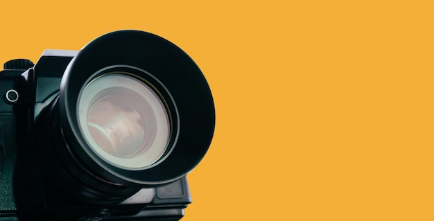 Photo front lens of vintage film camera with black body isolated on yellow background banner with copy space clipping path included