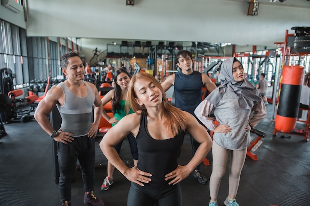 Front look group of people at the gym stretching to warm up