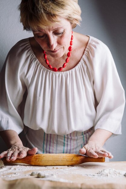 나무 롤링 핀으로 고기 만두를 만드는 여성의 손의 전면 중간 보기