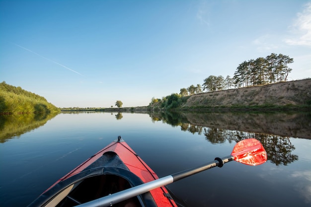 Front part of a canoe with a paddle floating on the river during the sunset