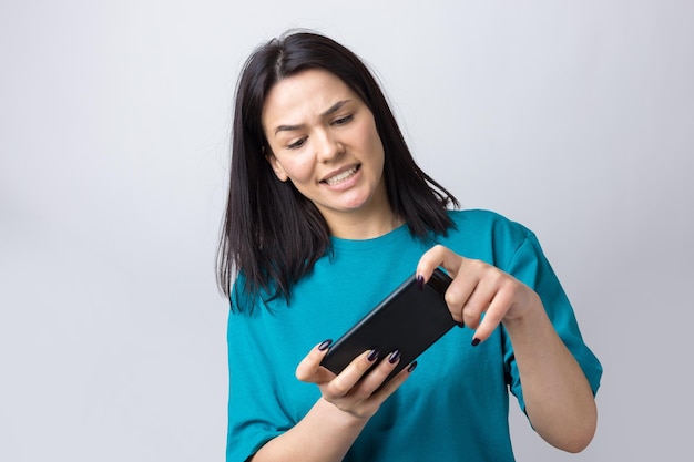 Ritratto frontale di giovane donna sorridente che utilizza il telefono cellulare su sfondo grigio