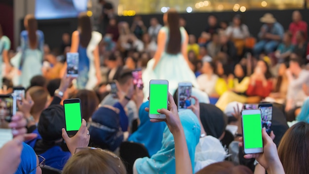 Front row VIP guests people from audience filming vdo fashion show with mobile smart phone