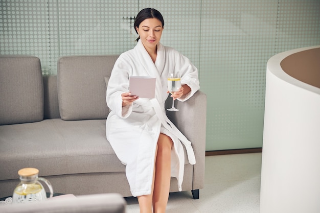 Front view of an attractive young spa client looking at a booklet in her hand