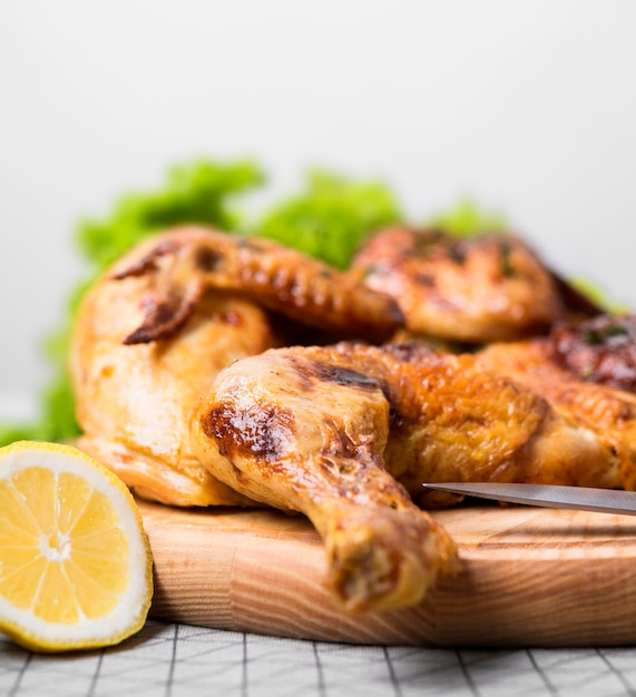 Front view baked whole chicken on cutting board with lemon