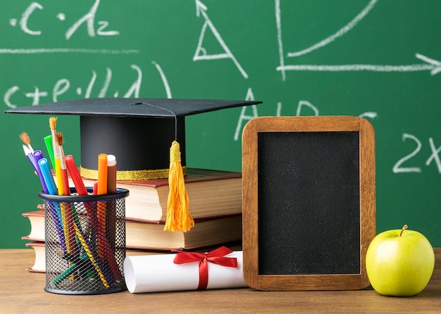 Photo front view of blackboard with academic cap and pencils