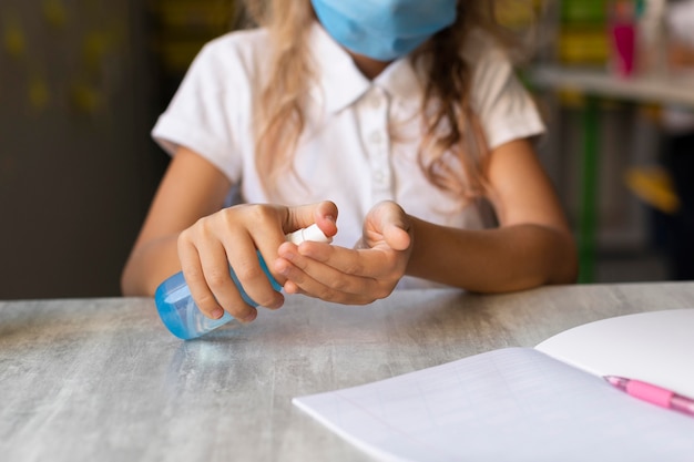 Photo front view blonde girl disinfecting her hands