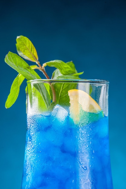 Front view blue cool lemonade with ice on the blue background water cold juice cocktail bar drink fruit color