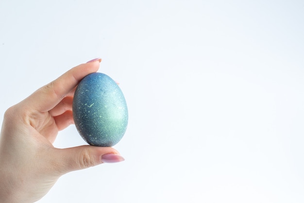 front view blue designed egg in female hand on white background spring colourful novruz holiday concept ornate