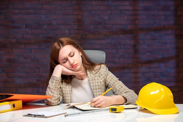 front view bored female engineer sitting behind her working place in construction site job agenda plan property business contractor success builder corporate