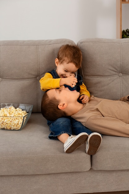 Photo front view brothers eating popcorn