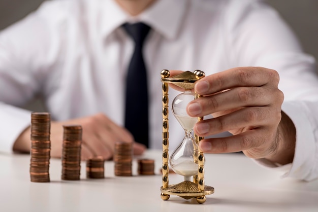 Photo front view of business man holding hourglass with coins