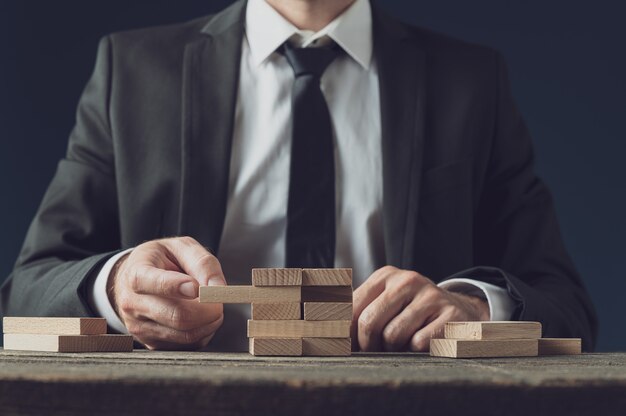 front view of businessman at his desk making a stack of wooden pegs