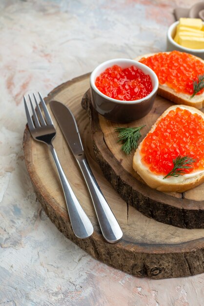 front view caviar sandwiches with cutlery on cutting board light surface