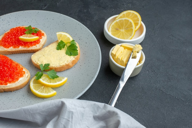 front view caviar sandwiches with lemon and cutlery inside blue plate on dark surface