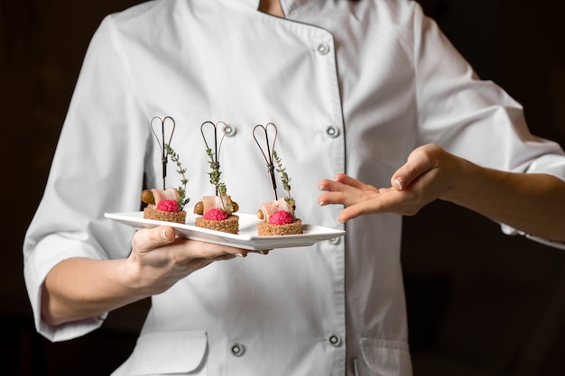 Foto vista frontale del cuoco unico che tiene un piatto dell'alimento