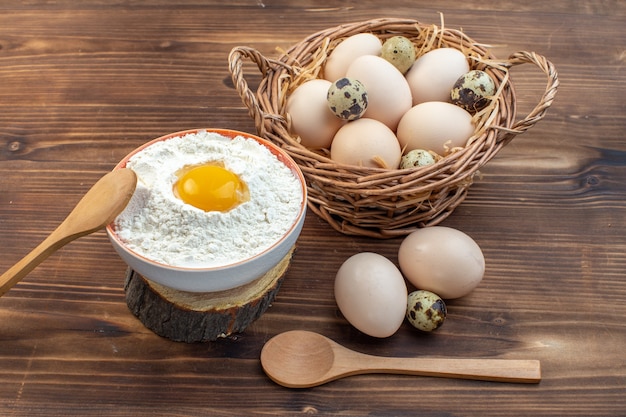 front view chicken eggs inside basket with flour on brown surface