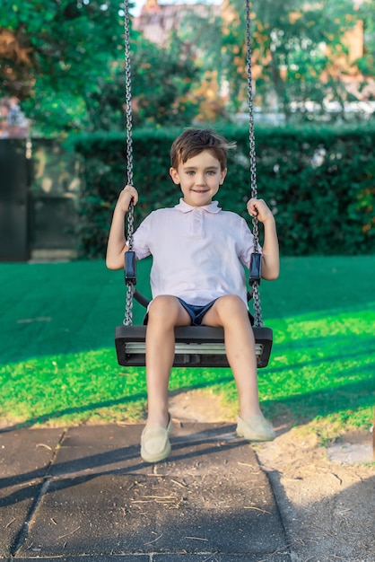 Front view of a child playing on a swing in a playground.