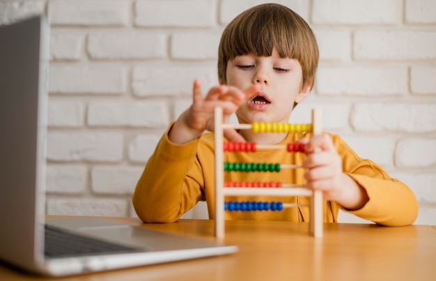 Photo front view of child using abacus with laptop