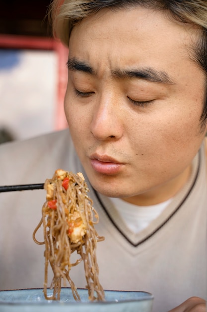 Foto uomo cinese di vista frontale che mangia le tagliatelle